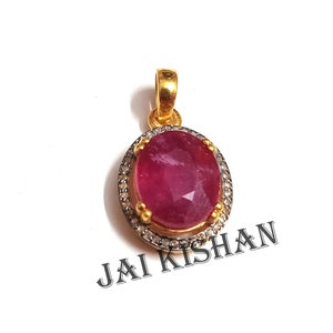 May include: A red oval gemstone pendant with a diamond halo setting. The pendant is made of gold and has a bail for attaching to a chain.