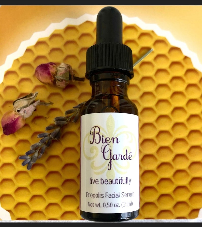 May include: A small amber glass bottle with a black dropper top. The bottle is labeled "Bien Gard&eacute;" with the text "live beautifully" and "Propolis Facial Serum". The bottle contains 0.50 ounces (15 ml) of serum.