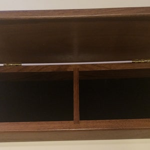 May include: A wooden box with a hinged lid, divided into two compartments lined with black velvet. The box is made of dark brown wood and has brass hinges.
