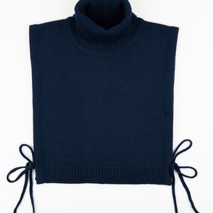 May include: A navy blue turtleneck sweater with a high neck and ties on the sides.