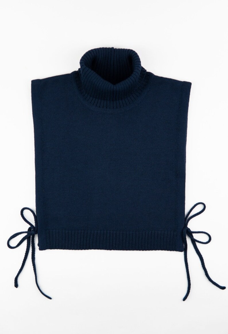 May include: A navy blue turtleneck sweater with a high neck and ties on the sides.