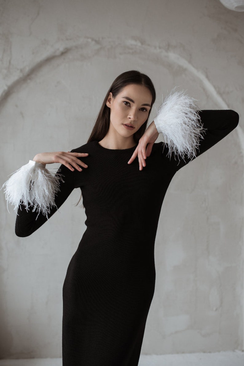 White ostrich feather cuffs on a black merino wool dress