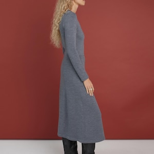 May include: A long-sleeved, mid-length dress in a heathered blue-gray knit fabric. The dress features a fitted bodice, a defined waistline, and a slightly flared skirt that falls below the knee. It is paired with black leather knee-high boots.