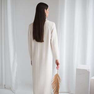 long turtleneck off white color knit merino wool dress. dark haired lady wearing this dress, back look.