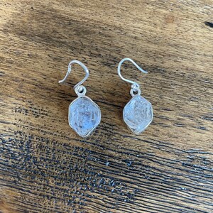 Puede incluir: Un par de pendientes de plata con piedras de cristal transparente en forma de lágrima.