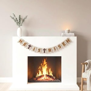 May include: A white fireplace with a burning fire inside. A banner that reads "HE IS RISEN" hangs above the fireplace. A white vase with green stems and a candle are on the mantel.