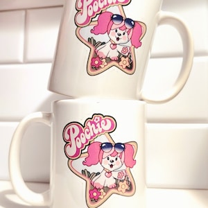 May include: Two white ceramic mugs with a pink cartoon dog wearing sunglasses and a pink bow. The dog is on a yellow star with the word "Poochie" in pink letters.