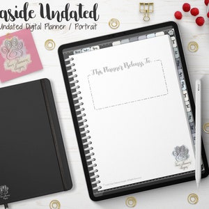 Puede incluir: Un planificador digital negro y un cuaderno negro se muestran sobre una superficie blanca, junto con una tableta que muestra un planificador digital. La tableta muestra el texto "This Planner Belongs To..." y "Seaside Undated". Clips dorados y frambuesas están dispersos.