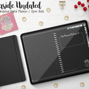 Puede incluir: Un planificador digital negro y un cuaderno negro a juego se muestran sobre una superficie de madera blanca. El planificador digital está abierto, revelando un interior gris oscuro con una sección etiquetada como "This Planner Belongs To". El texto "Seaside Undated" está en la parte superior.