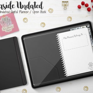 Puede incluir: Un planificador digital abierto con el texto "Seaside Undated" y "Undated Digital Planner / Open Book". También hay un cuaderno negro y una tableta con un lápiz óptico. La página del planificador dice "This Planner Belongs To..."