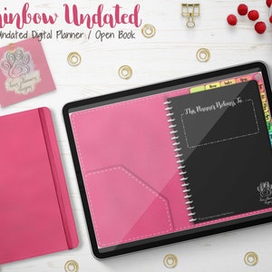 Puede incluir: Un planificador digital con el texto "Rainbow Undated" y "Undated Digital Planner / Open Book". El planificador se muestra en una tableta con una cubierta rosa y un interior negro. También se ven un cuaderno rosa y una tarjeta pequeña.