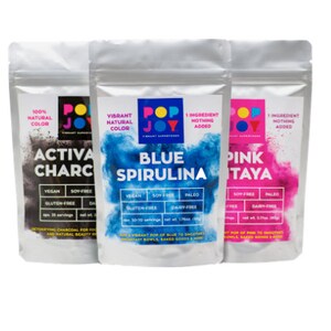 Op de afbeelding: Drie zakjes met natuurlijk voedselkleurpoeder. De zakjes zijn gelabeld met "Activa Charcoal", "Blue Spirulina" en "Pink Pitaya". Elk zakje heeft een afbeelding van een levendige kleurwolk en vermeldt de ingredi&euml;nten als "1 ingredi&euml;nt, niets toegevoegd".