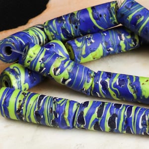 May include: A strand of blue and green glass beads with a marbled pattern. The beads are cylindrical and have a rough texture.