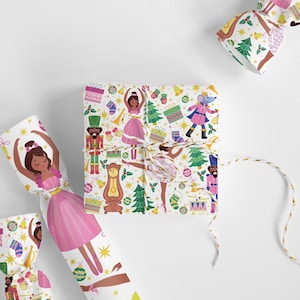May include: White wrapping paper with a repeating pattern of a ballerina, nutcracker, Christmas tree, and other holiday decorations. The paper is tied with a brown twine bow.