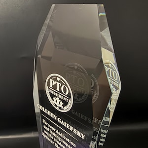Op de afbeelding: Een heldere, gefacetteerde acryl award trofee met een gegraveerd rond logo met de tekst PTO PRESIDENT. Onder het logo staat de tekst COLLEEN GAIEFSKY, gevolgd door een inscriptie die toewijding en blijvende impact erkent.