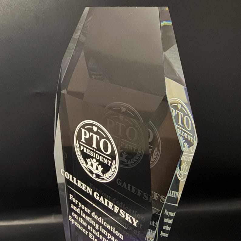 Op de afbeelding: Een heldere, gefacetteerde acryl award trofee met een gegraveerd rond logo met de tekst PTO PRESIDENT. Onder het logo staat de tekst COLLEEN GAIEFSKY, gevolgd door een inscriptie die toewijding en blijvende impact erkent.