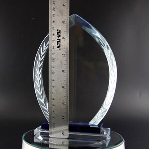 K&ouml;nnte beinhalten: Eine klare Glas-Troph&auml;e mit blauer Basis und einem mattierten Lorbeerkranz-Design. Die Troph&auml;e ist 30,5 cm hoch.