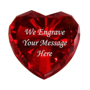Può includere: Un cuore di cristallo rosso con il testo "We Engrave Your Message Here" inciso sul davanti.