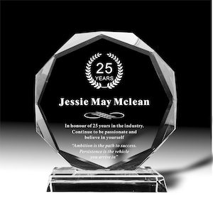 Könnte beinhalten: Eine klare, facettierte Kristallauszeichnung mit schwarzem Innenraum. Die Auszeichnung zeigt den Text "25 JAHRE" in einem Lorbeerkranz, den Namen "Jessie May McLean" und inspirierende Zitate. Die Auszeichnung steht auf einem rechteckigen Sockel.