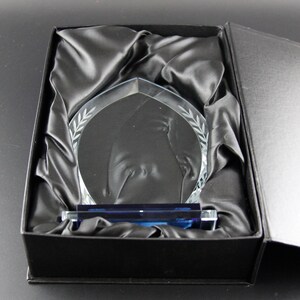 K&ouml;nnte beinhalten: Eine klare Glas-Troph&auml;e mit blauer Basis, die ein Design einer Person beim Golfspielen zeigt. Die Troph&auml;e befindet sich in einer schwarzen, mit Samt ausgekleideten Box.