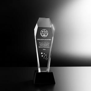 Op de afbeelding: Een heldere, taps toelopende glazen trofee met een zwarte voet. Het glas is gegraveerd met de tekst PTO PRESIDENT, COLLEEN GALEFSKY, For your dedication and lasting impact on the students of Spencer Elementary, 2026, en een groep sterren.