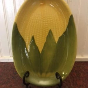 May include: A white ceramic mug with a black handle and the text "But First, Coffee" in a black, handwritten-style font. The mug is on a white surface.