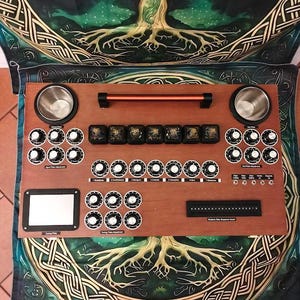 May include: A rectangular wooden radionics device featuring a top handle, two metal bowls, and numerous black control knobs with white markings. The interface includes a small screen, a numeric sequence insert, and labels for input, output, and tuning plate adjustments.
