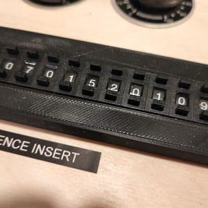 May include: A black sequence insert with white numbers and the text "SEQUENCE INSERT". The insert has a series of rotating number dials from 0 to 9. The insert is secured with two screws.