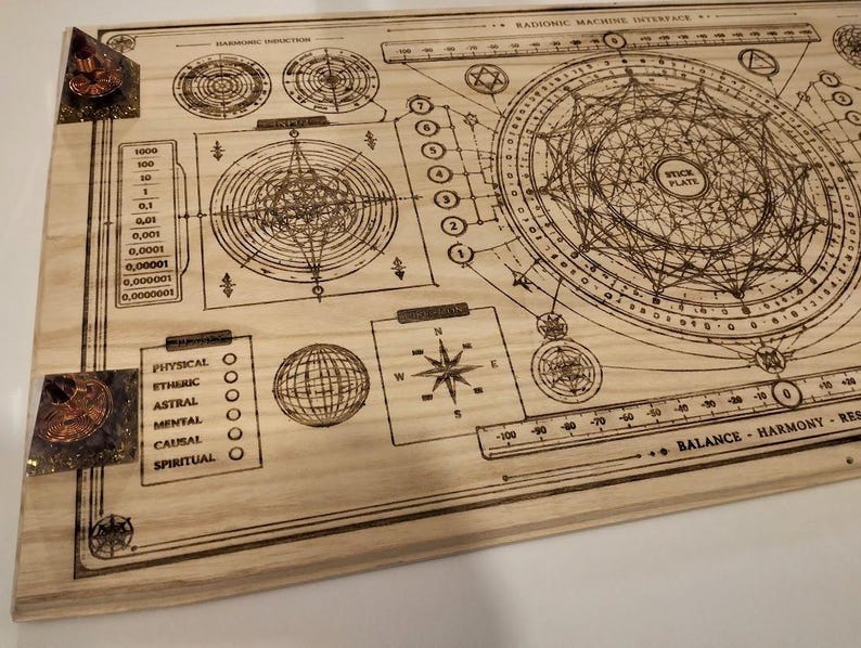 May include: A wooden board with intricate etched designs, including geometric shapes, circles, and text. The board features a compass rose, a globe, and a scale. Two corners have embedded crystals. The text includes "Harmonic Induction" and "Balance - Harmony - Res".