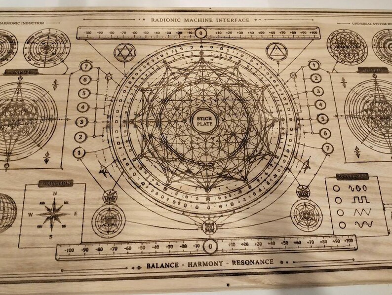 May include: A wooden board with a complex geometric design, featuring circles, lines, and text. The text includes "RADIONIC MACHINE INTERFACE", "STICK PLATE", and scales with numbers. The design is etched into the light-colored wood, creating a detailed, technical aesthetic.