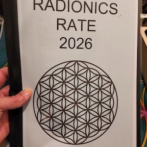May include: A light blue paper with the words "RADIONICS RATE 2026" in black font. Below the text is a black and white geometric design of interlocking circles, held in a black binder.