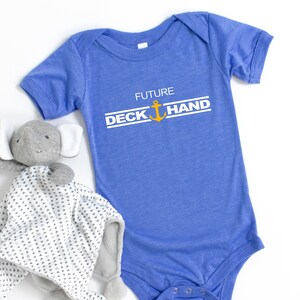 May include: A blue baby onesie with the text "FUTURE DECK HAND" in white with a gold anchor in between the words.