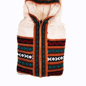 May include: A cream-colored hooded sweater with a zipper closure and a colorful geometric pattern around the waist.