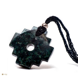 Könnte beinhalten: Ein Anhänger aus grünem Jade-Stein in Form eines vierzackigen Sterns mit einem Kreis in der Mitte. Der Anhänger ist an einer schwarzen Schnur.
