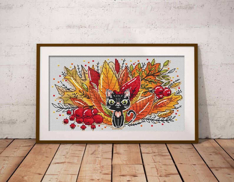 May include: A black cat with green eyes sits in a pile of colorful autumn leaves. The leaves are red, orange, and yellow. There are also some red berries in the image.