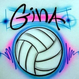 May include: A white volleyball with black lines, surrounded by blue and pink paint splatters. The word "GINA" is written in black cursive above the volleyball.