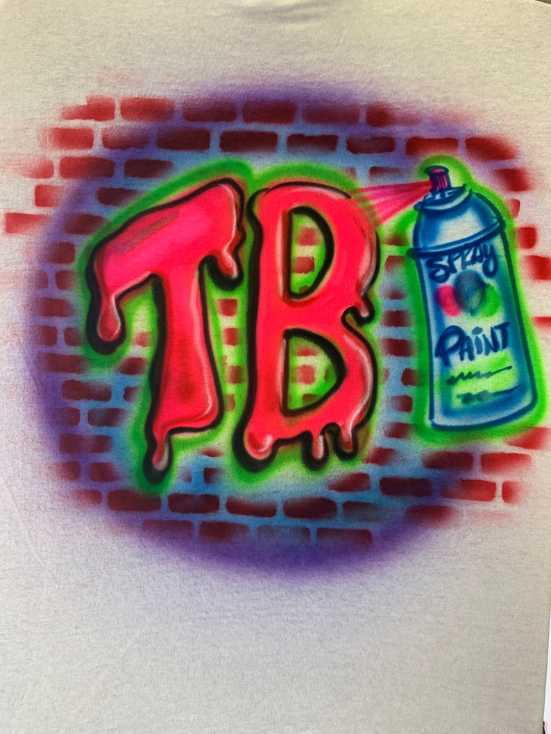 May include: A spray paint can with a blue and white design is spraying pink paint onto a brick wall with the letters "TB" in a dripping style.