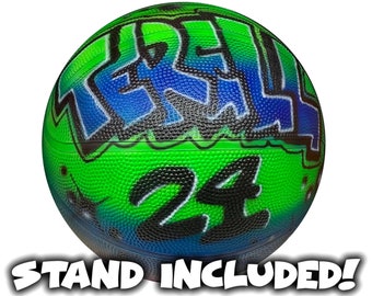 May include: Green and blue basketball with black graffiti and the number 24. The basketball comes with a stand.