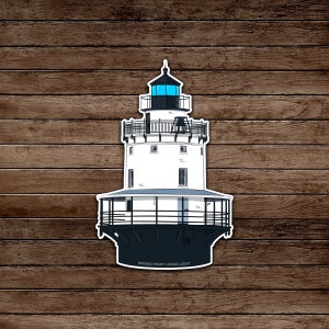 May include: A sticker featuring a detailed illustration of the Spring Point Ledge Light. The lighthouse is white with black accents, a blue light, and the text "SPRING POINT LEDGE LIGHT" at the base. The background is a wood grain pattern.