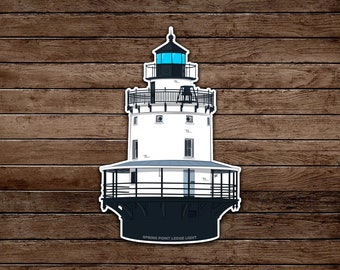 May include: A sticker depicting the Spring Point Ledge Light. The lighthouse is white with black detailing and a blue light. The text "SPRING POINT LEDGE LIGHT" is at the base. The background is a wood grain effect.