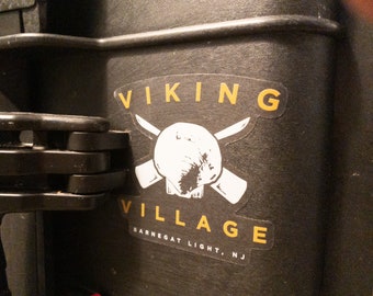 May include: A white sticker with a skull and crossbones design. The text "VIKING VILLAGE" is in yellow above the skull and "BARNEGAT LIGHT, NJ" is in yellow below the skull.