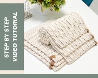 May include: Cream-colored crochet placemats with a textured, ribbed design. The placemats are stacked and rolled, with leather tags attached. The image includes text that reads "CROCHET PLACEMAT", "STEP BY STEP VIDEO TUTORIAL", and "PERFECT FOR BEGINNERS".