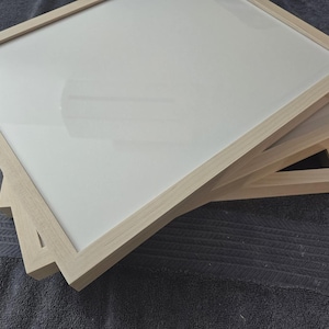 May include: A stack of three wooden picture frames with a light-colored finish. Each frame has a clear glass or acrylic insert. The frames are square and appear to be new.