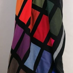 May include: A black throw blanket with a geometric pattern of colorful squares. The squares are in shades of red, orange, green, blue, purple, and brown.