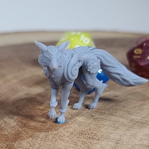 May include: A gray, detailed, 3D printed miniature of a wolf with a long, flowing tail. The wolf is standing on a wooden surface with dice in the background.