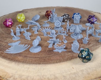 May include: A collection of 3D printed miniature figurines for tabletop role-playing games, including a skull, a tree, a lantern, a shield, a tombstone, and a dragon. The figurines are painted in a light gray color and are arranged on a wooden surface. There are also several dice in the image, including a purple d20, a yellow d20, a blue d20, and a green d20.