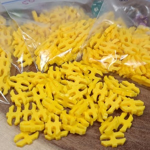 May include: A close-up of three bags filled with yellow plastic sprinkles shaped like the letter "H".