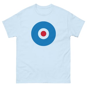Puede incluir: Camiseta azul claro con un diseño gráfico grande y centrado. El diseño presenta un círculo azul con un círculo interior blanco y un punto rojo en el centro. La camiseta tiene mangas cortas y cuello redondo.