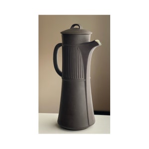 May include: A tall, dark brown ceramic coffee pot with a lid and handle. The pot has a ribbed design on the upper portion and a long, slender spout. The pot is approximately 12 inches tall.