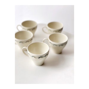 Peut inclure: Ensemble de cinq tasses à café en céramique blanche avec un motif floral bleu et vert. Les tasses ont une forme arrondie et une petite poignée.